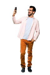 Full-length shot of Handsome man with beard making a selfie over isolated white background