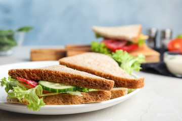 Fototapeta na wymiar Tasty fresh sandwiches with cucumbers and sausage on light grey table, closeup