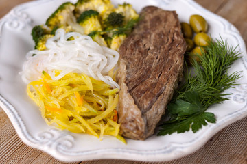 Grilled cooked beef meat, broccoli, vegetable spaghetti shirataki, olives ketogenic diet dish