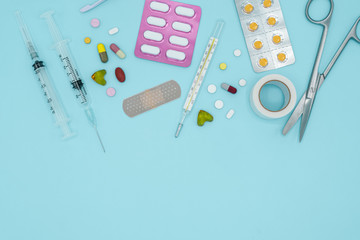 Top view of pills and medical tools on blue background with copy space, medical and healthcare concept.