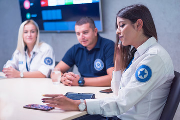 Group of security guards working on computers while sitting in the main control room, CCTV surveillance.