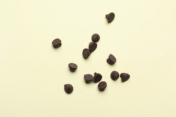 Delicious chocolate chips on beige background, top view