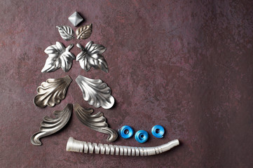 Alternative Christmas tree made of metal, decorative elements in the form of leaves and streamers of white and blue on a textured, lilac background.  Horizontal layout, copy space, top view.