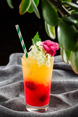 Delicious cocktail with orange juice and Red Tequila Sunrise, ice cubes in a glass on gray background restaurant. Exotic red summer drink. Bar alcohol menu, enjoy. vertical