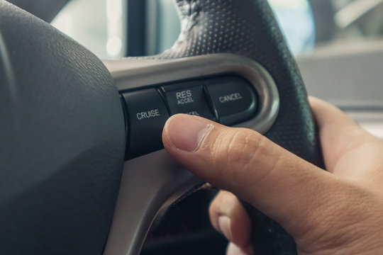Hand pushes cruise control button on steering wheel and speed limitation.