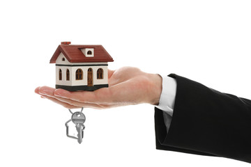 Fototapeta na wymiar Real estate agent holding house model and key on white background, closeup