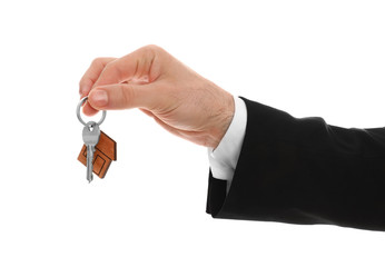 Real estate agent holding house key with trinket on white background, closeup