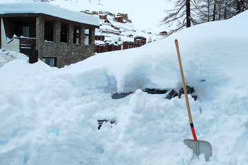 After huge snowfall in January 2018, valtournenche, cervinia, Italy. A car under a snowdrift and a shovel in the foreground