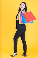 Happy shopper smiling in dark suit with shopping bag on yellow background using as business shopping online concept.