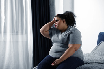 Depressed overweight woman on bed at home