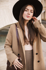Portrait of brunette young fashion woman in autumn coat walking outdoors