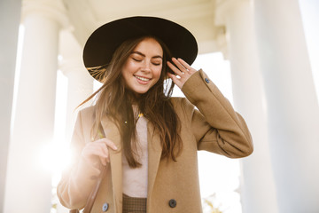 Portrait of happy woman smiling while standing by pillars outdoors