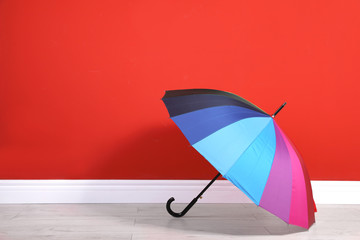 Beautiful colorful umbrella near red wall. Space for text