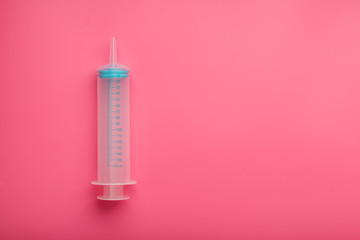 Medical syringe on cyanide, pink background close-up, copy space. The concept of minimalism.