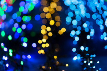Fototapeta na wymiar Defocused christmas garlands with colorful glow. Christmas background with multicolored bokeh.
