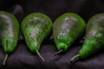 Fresh pears green with drops of water on the rind lie on a black background of a horizontal photo