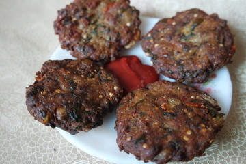 Delicious spicy fried round kebab served in white ceramic plate with red sauce.