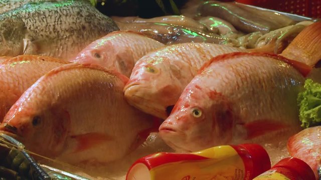 An extreme closeup shot of a pile of fresh redfish snapper on display at a wet market along with other types of raw fishes.