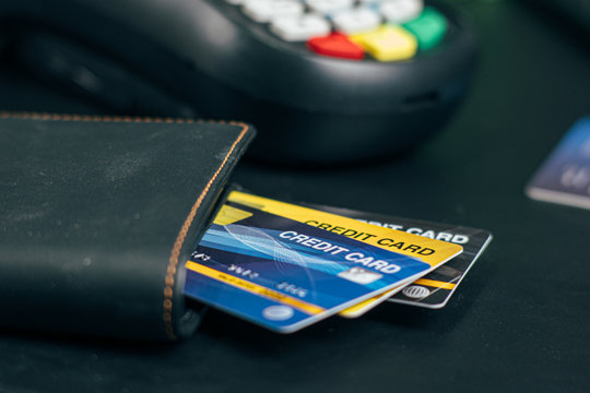  Stacked credit cards on table with Credit card reader machine or Payment terminal