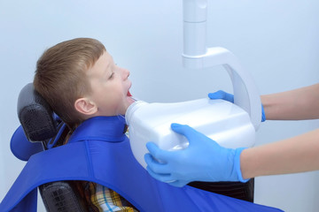 Making x-ray of teeth for teenage boy in dentistry clinic, side view. Dentist scaning jaw on x-ray...