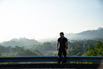 determined man, explorer pathfinder forest, military man forest, man with tactical gear at the cliff with mountain view, cool guy forest.