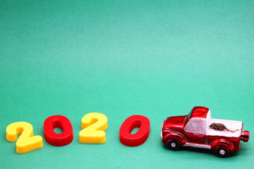 A small metal mouse on a red toy car next to the numbers 2020. The mouse is a symbol of The new year 2020 according to the Chinese calendar.