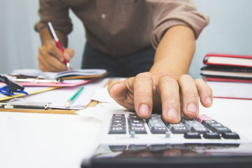 businessman using calculator and holding pen on tax paper in office.Accounting.concept.