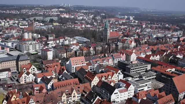 City of Ulm from the view point of Ulm Cathedral on a sunny March day. White houses with red roofs, people walk around the streets and drive cars