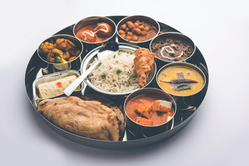 Indian vegetarian Food Thali or platter includes paneer butter masala, dal makhani / tarka, chole papad, kofta curry, gulab jamun, aloo-gobi sabji, chapati and rice with Bengali sweet served - obrazy, fototapety, plakaty