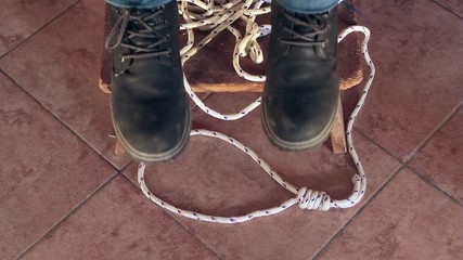 feet of a hanged dead man dangling with the stool and the rope used to hang himself