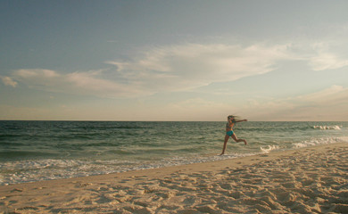 Girl Dancing on the Beach in the sand by the surf at sunset