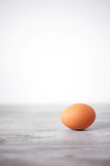 Whole brown egg solitary on gray wooden background