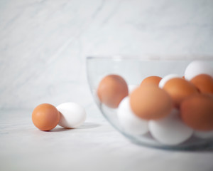 Whole white and brown eggs in glass bowl