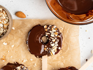 Delicious fresh Red Apple slices in melted chocolate with chopped almond nuts on wooden popsickle sticks, White background, healthy dessert. 