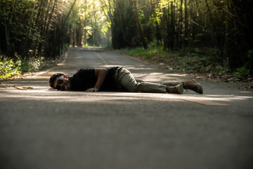 crazy man lying down and licking on asphalt road in bamboo forest side way