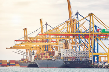 Ship-to-shore cranes unloading containers from a ship in harbor enviroment. Transportation industry...