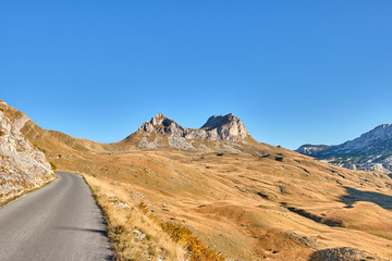 Naklejka na ściany i meble Rocky mountains covered with autumn meadow against the blue sky