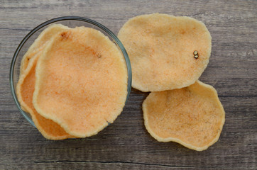 Prawn crackers in a glass bowl isolated on wooden background.