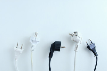 Electrical plugs from electrical appliances in white and black on a white background. View from...