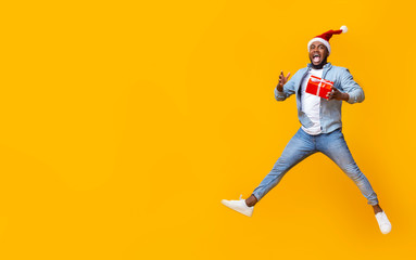 Fototapeta na wymiar Funny black man jumping with christmas gift box