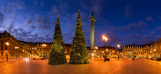 Panoramic view of Place Vendome with Christmas trees and holiday decorations at dusk. In the center, the Vendome column with the statue of Napoleon. 1st Arrondissement, Paris, France