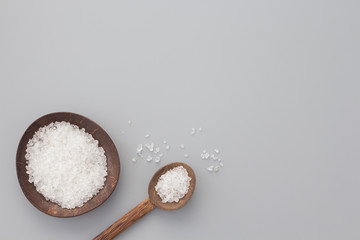 White bath salt in bowl and spoon from coconut shell on gray background. Natural spa products...