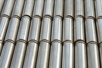 Metal parts with shiny silver steel cylindrical surface closeup. View of the disassembled lithium ion form factor cell 2170 battery pack. Abstract Industrial background with selective soft focus.