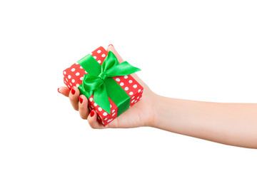 Woman hands give wrapped Christmas or other holiday handmade present in red paper with Green ribbon. Isolated on white background, top view. thanksgiving Gift box concept