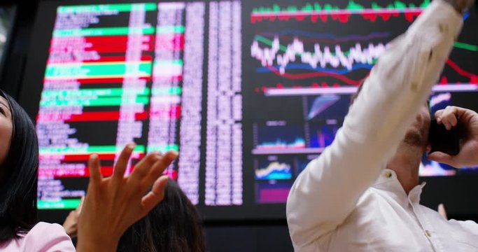 4K Hyped up male & female stock exchange traders buying & selling over the phone