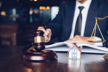 Real Estate Law concept. Gavel on sounding block in hand's Male judge at a courtroom, working for the insurance compensations. report the case on table in modern office.