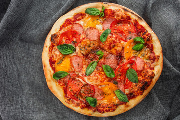 Delicious hot homemade pizza on the wooden table. Pizza - Fresh homemade pizza with pepperoni, cheese and tomato sauce, tomatoes, and basil with copy space. Horizontal