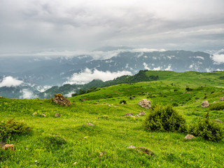 Fototapeta na wymiar Green hillsides with scattered rocks. Summer mountain landscape