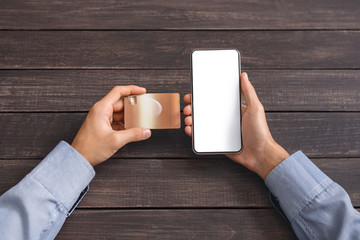 Man's hands holding credit card and cellphonewith blank screen