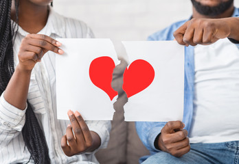 Black couple ripping paper with red heart symbol into halves